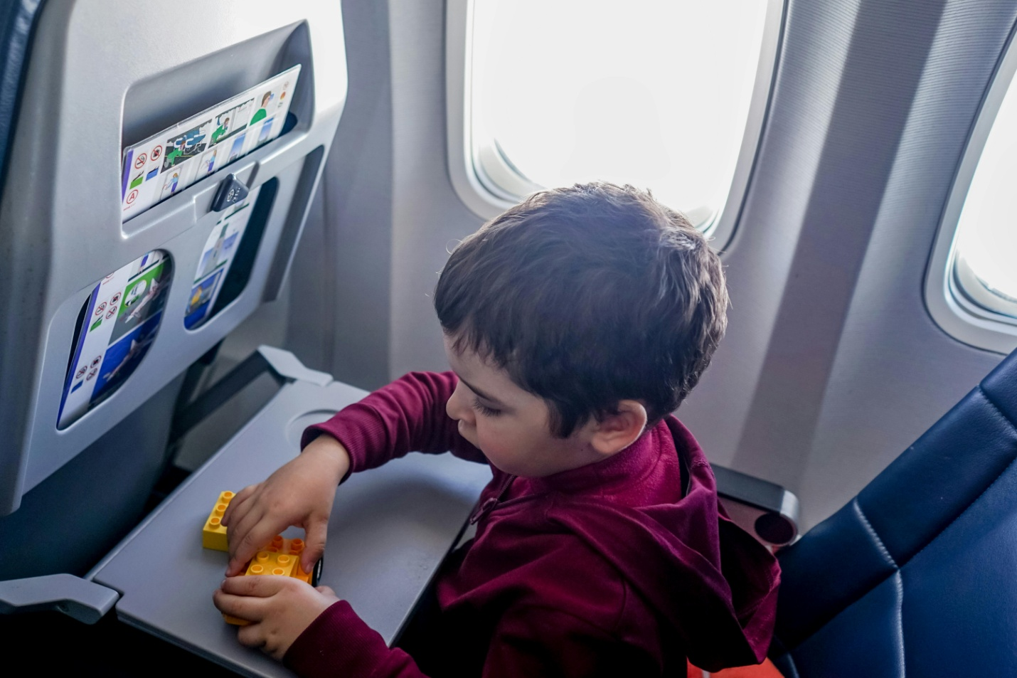 A little boy playing with blocks on a plane.