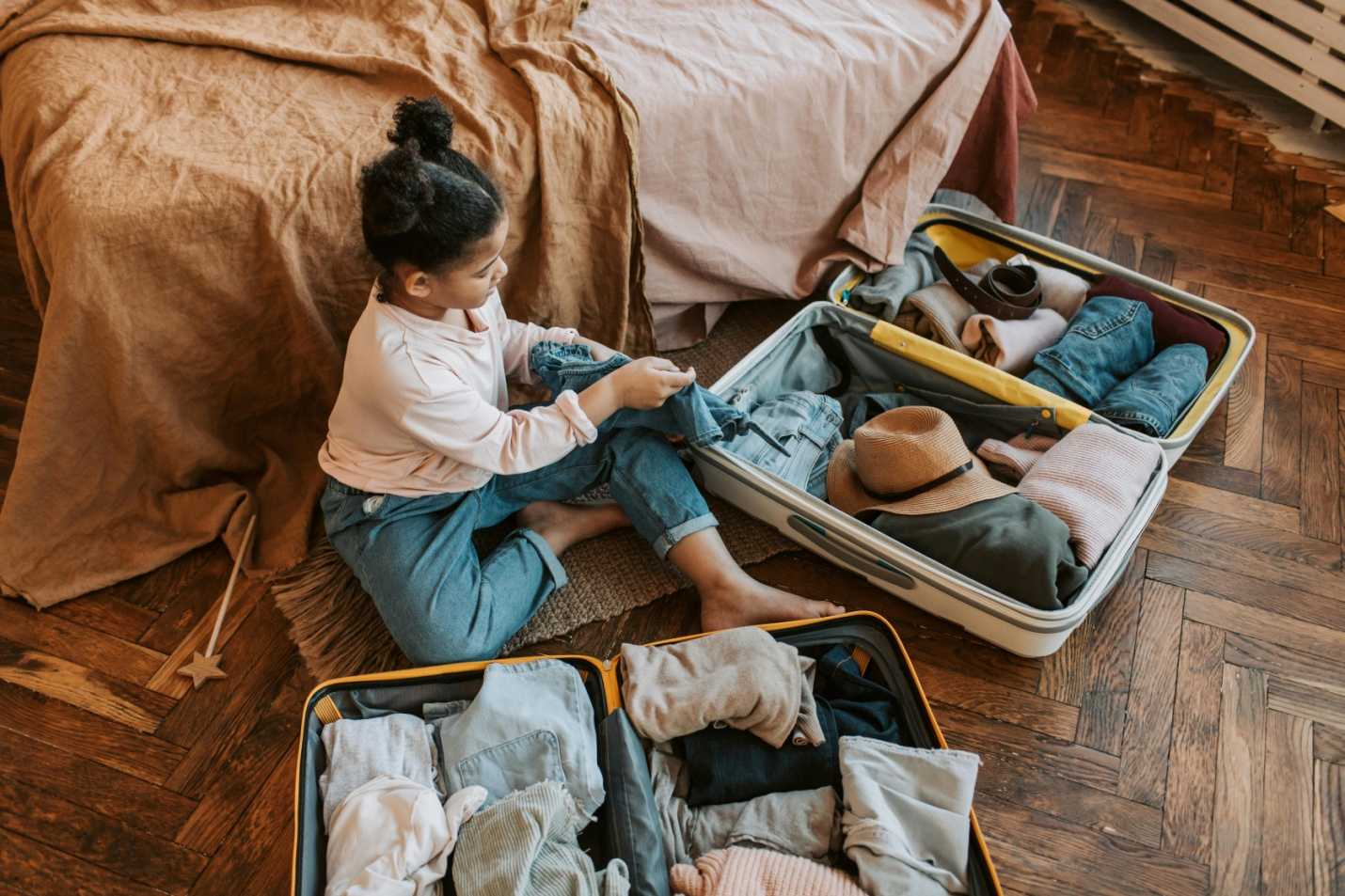 A little girl packing a suitcase.