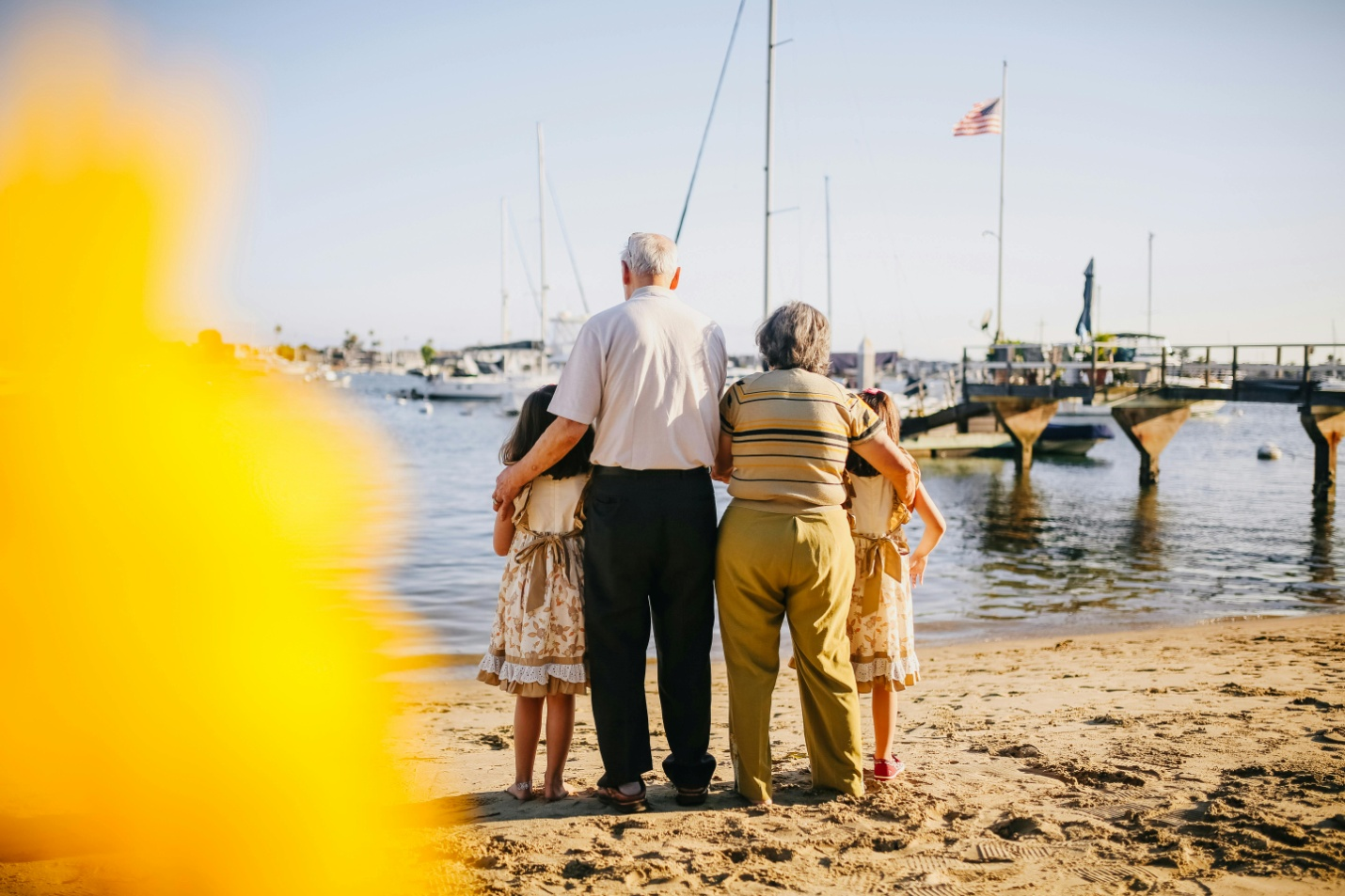 Two kids with their grandparents standing by the shore.