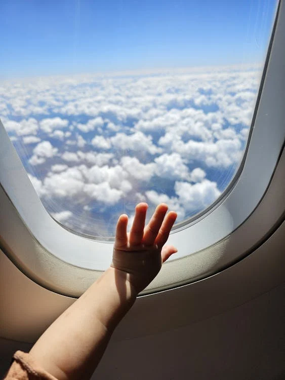 A child’s hand on the plane window 