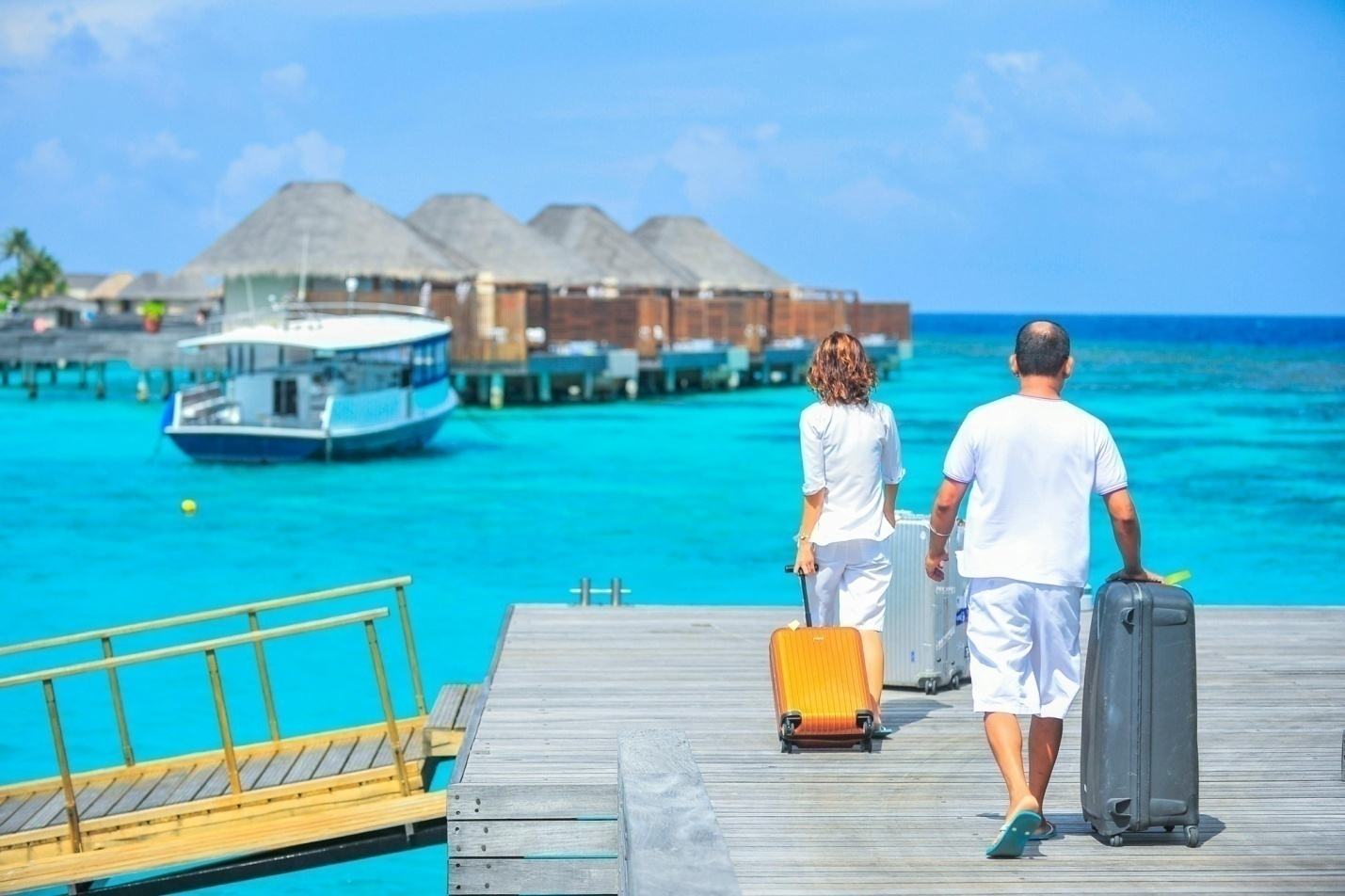 Two people walking on a dock while carrying luggage