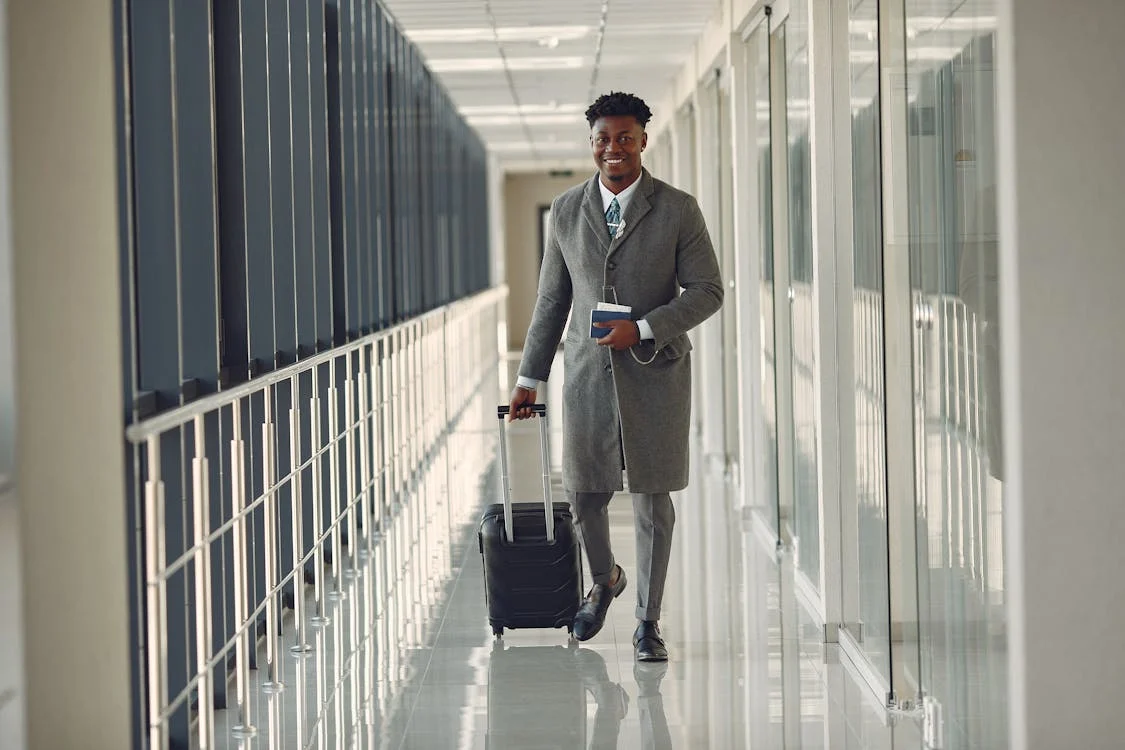 A man walking in an airport with his suitcase and passport 