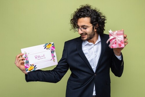handsome-man-suit-holding-greeting-card-present-looking-card-happy-positive-smiling-cheerfully-celebrating-international-women-s-day-march-8-standing-green-background_141793-67902.jpg